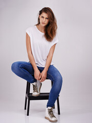 Simple style suits me fine. Studio portrait of an attractive young woman sitting on a chair.