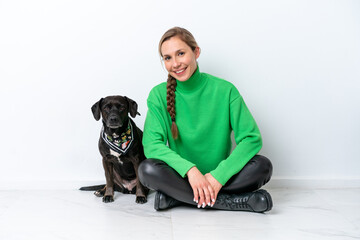Young caucasian woman sitting on the floor with his puppy isolated on white background smiling a lot