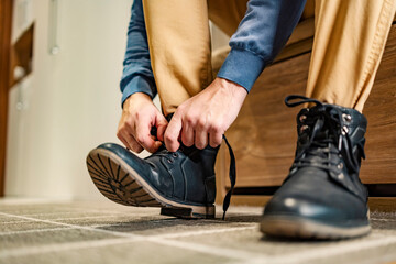 Close up of a man tying his laces on shoes at home. - obrazy, fototapety, plakaty