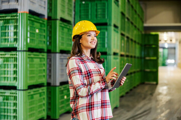 A female manager looking around factory and scrolling on tablet.