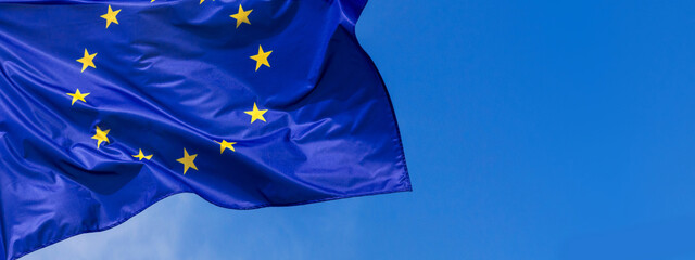 Flag of the European Union waving in the wind on flagpole against the sky with clouds on sunny day, banner, close-up - obrazy, fototapety, plakaty
