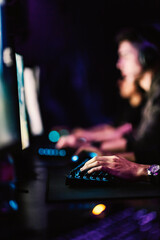Hands typing commands on keyboard in dark gaming room. E-sport concept.