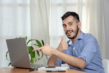 Successful office worker cheers and smiles while looking at his computer. Office work.