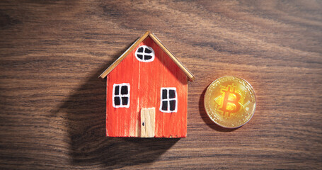 Obraz na płótnie Canvas Bitcoin and house model on the wooden table.