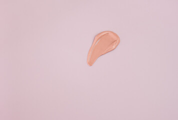 close-up of a smear of foundation on a pink background.