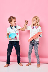 Stylish little boy and cute girl are playing together pink color background