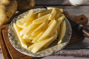 Dish with raw cane potatoes to make french fries. Chopped or high view.