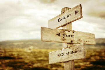 boost your confidence text quote written in wooden signpost outdoors in nature. Moody theme feeling.
