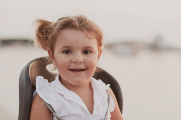 A portrait of a smiling little girl sitting in a bicycle seat. Selective focus 