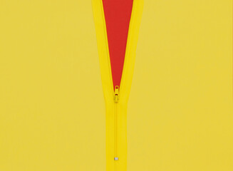 Yellow zipper unzipped half way showing red color under a yellow background.