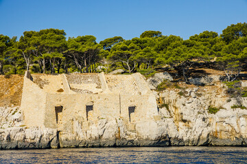 Fototapeta na wymiar Coastline of the Calanque de Port-Miou and remains of old limestone quarries in Cassis Provence seen from an excursion boat cruising on the Mediterranean sea in France
