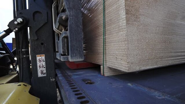 forklifts load pallets with OSB boards into a freight train car. business logistics concepts, import and export concepts. close up