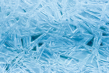 Texture frozen natural blue ice crystals closeup, top view. Ice patterns on the water surface...