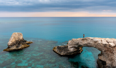 Woman standing at lovers bridge enjoying the scenery of the sea at sunset. Ayia Napa Cyprus