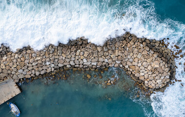 Aerial drone of stormy windy waves hitting with power the breakwater. Extreme weather at sea.