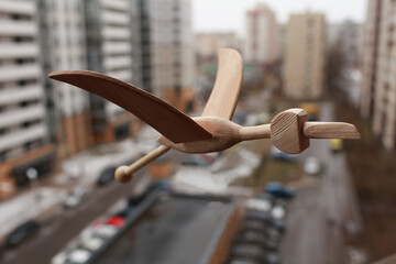 wooden bird toy flying over the city close-up