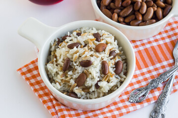 Cooked rice pilaf with red beans on white surface on cloth napkin