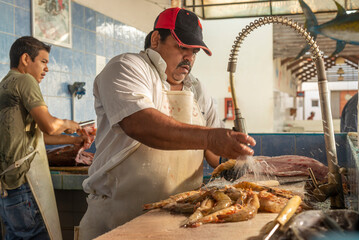 Latin butchers cleaning fish and shrimps at the local fish market