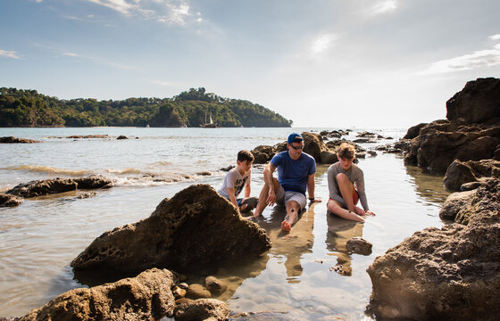 Father and sons playing in water on beach on vacation in Costa Rica.