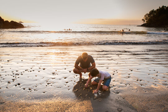 Father and son playing on the beach at sunset in Costa Rica.