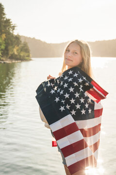 Young Girl Wrapped in American Flag on Sunny Summer Day