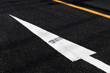 アスファルトの道路に描かれた白い矢印と黄色い線