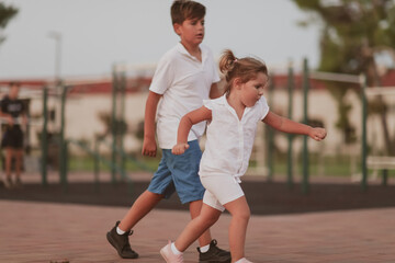 A little girl and brother in modern summer clothes playing in the park in summer. Selective focus 