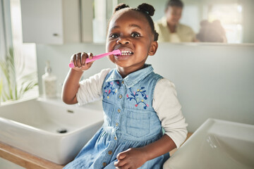 Caring for her cute little smile. Portrait of an adorable little girl brushing her teeth in the bathroom at home.