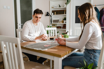 Obraz na płótnie Canvas Two people man and woman young couple husband and wife brother and sister or boyfriend and girlfriend playing cards at home in bright day real people leisure games concept having fun copy space