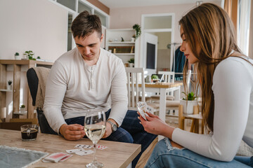 Two people man and woman young couple husband and wife brother and sister or boyfriend and girlfriend playing cards at home in bright day real people leisure games concept having fun copy space