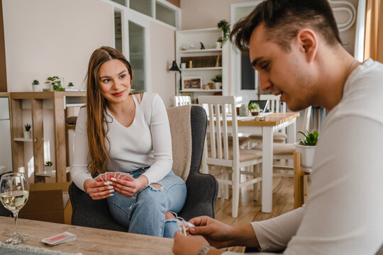 Two people man and woman young couple husband and wife brother and sister or boyfriend and girlfriend playing cards at home in bright day real people leisure games concept having fun copy space