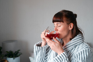 Theres just something about green tea.... Cropped shot of an attractive young woman drinking green tea in her bedroom at home.