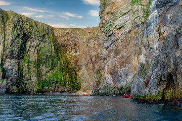 A zodiacs cruise along side of picturesque massive rocky cliffs in Bear Island Norway