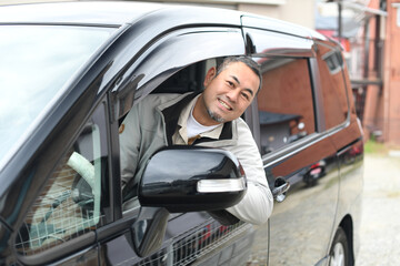 Fototapeta na wymiar 車を運転をする笑顔のミドル男性（カメラ目線）