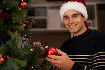 Setting up the tree. Shot of a handsome young man getting ready for Christmas.