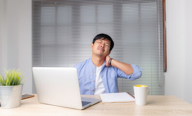 Fototapeta premium businessman is tired from working on his desk , feeling eyestrain, sitting at work desk, young man suffering from dry eye syndrome, fatigue after long laptop use and stress