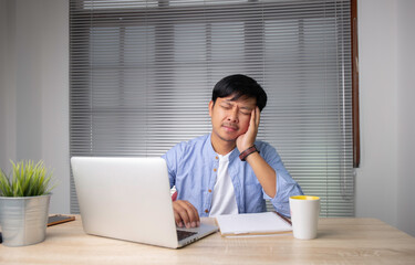 Fototapeta premium businessman is tired from working on his desk , feeling eyestrain, sitting at work desk, young man suffering from dry eye syndrome, fatigue after long laptop use and stress