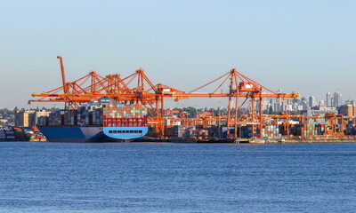 Place for loading ocean ships in the seaport of Vancouver, against the backdrop of a blue cloudy sky and a mountain range. North Vancouver at the foot of the mountain range