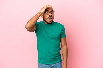 Young Colombian handsome man isolated on pink background doing surprise gesture while looking to the side