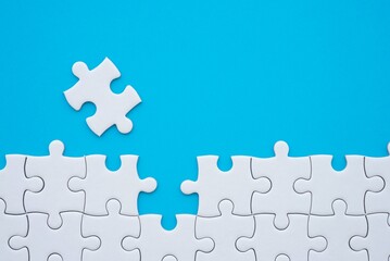 The last piece of jigsaw puzzle to complete task on blue background. Business strategy teamwork,...
