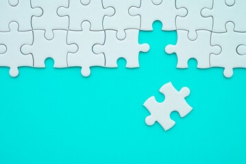 The last piece of jigsaw puzzle to complete task on blue background. Business strategy teamwork,...