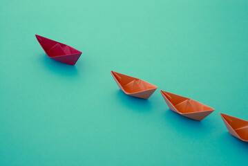 Leadership concept. Red paper boat origami motivate meeting with small orange boat on blue...