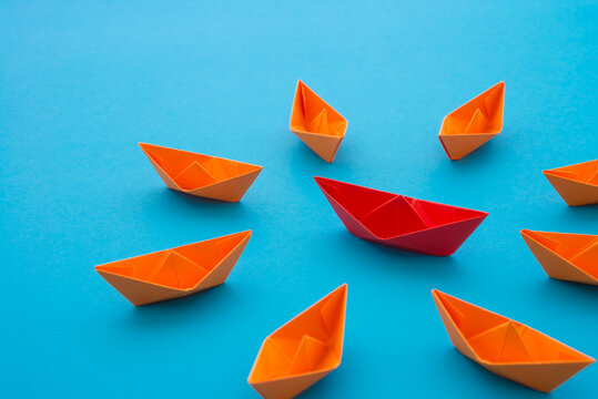 Leadership concept. Red paper boat origami motivate meeting with small orange boat on blue background. Leadership skills need for top management in organization, company ex. supervisor, manager, CEO