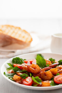 Fresh salad of shrimps, tomatoes, arugula and herbs on a white plate. vertical image