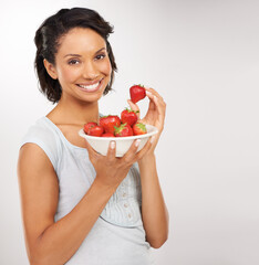 Sweet, juicy and absolutely delicious. Portrait of a young woman enjoying a bowl of strawberries.