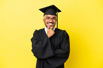 Young university graduate Colombian man isolated on yellow background with glasses and smiling