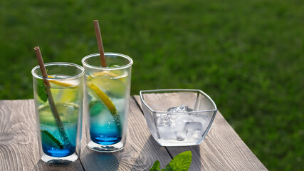 Two glasses with summer cool blue lagoon cocktail on a wooden table. Selective focus