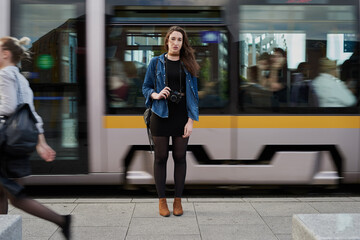 Obraz premium I have arrived. Portrait of an attractive young female photographer standing on the subway with a train passing through in the background.