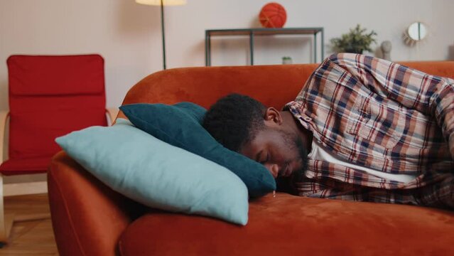 Exhausted overworked african american young man came home after work falling asleep on sofa feels like squeezed lemon. Concept after party, tired overworked person hard day, lack of energy, breakdown