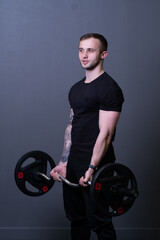 Fototapeta na wymiar Guy with a barbell in a black fitness T-shirt muscular bodybuilder heavy fit, for strength athlete from gym for handsome body, caucasian portrait. Lifting young motivation, health arm